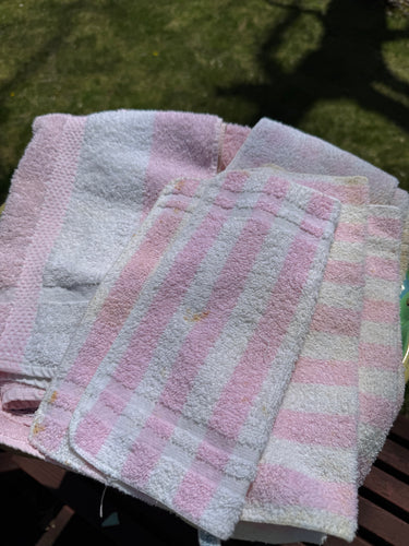 Stack of vintage pink and white striped towels on a grassy background